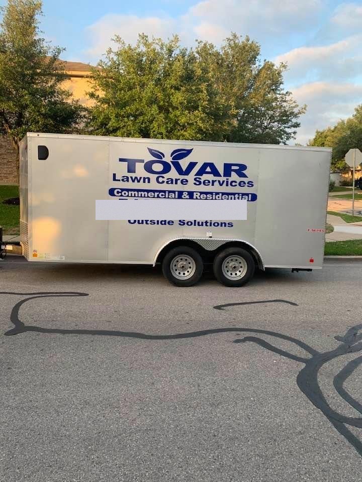 Tovar Lawn Care Services branded work trailer parked on a residential street